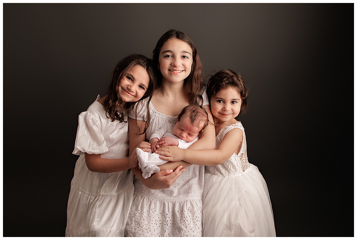 Older siblings cuddle newborn baby close for Yaffa Koff Photography