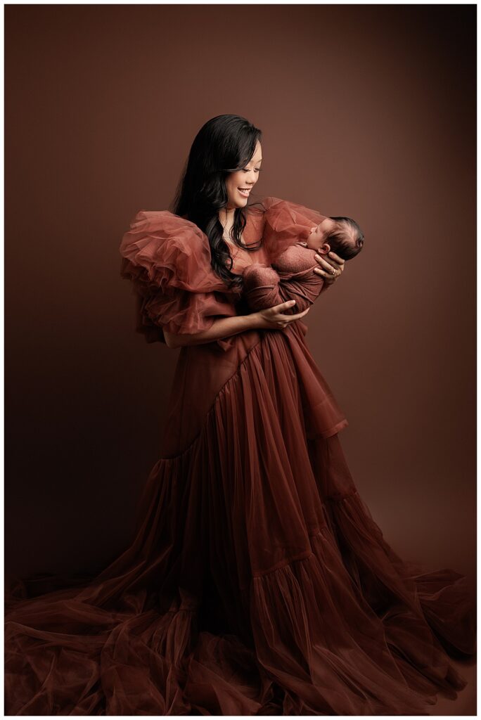 Mom smiles at sleepy newborn showing the Best Time For Your Newborn Session