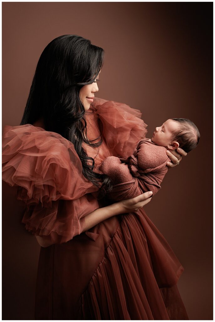 Mom holds sleepy newborn with a big smile showing the Best Time For Your Newborn Session