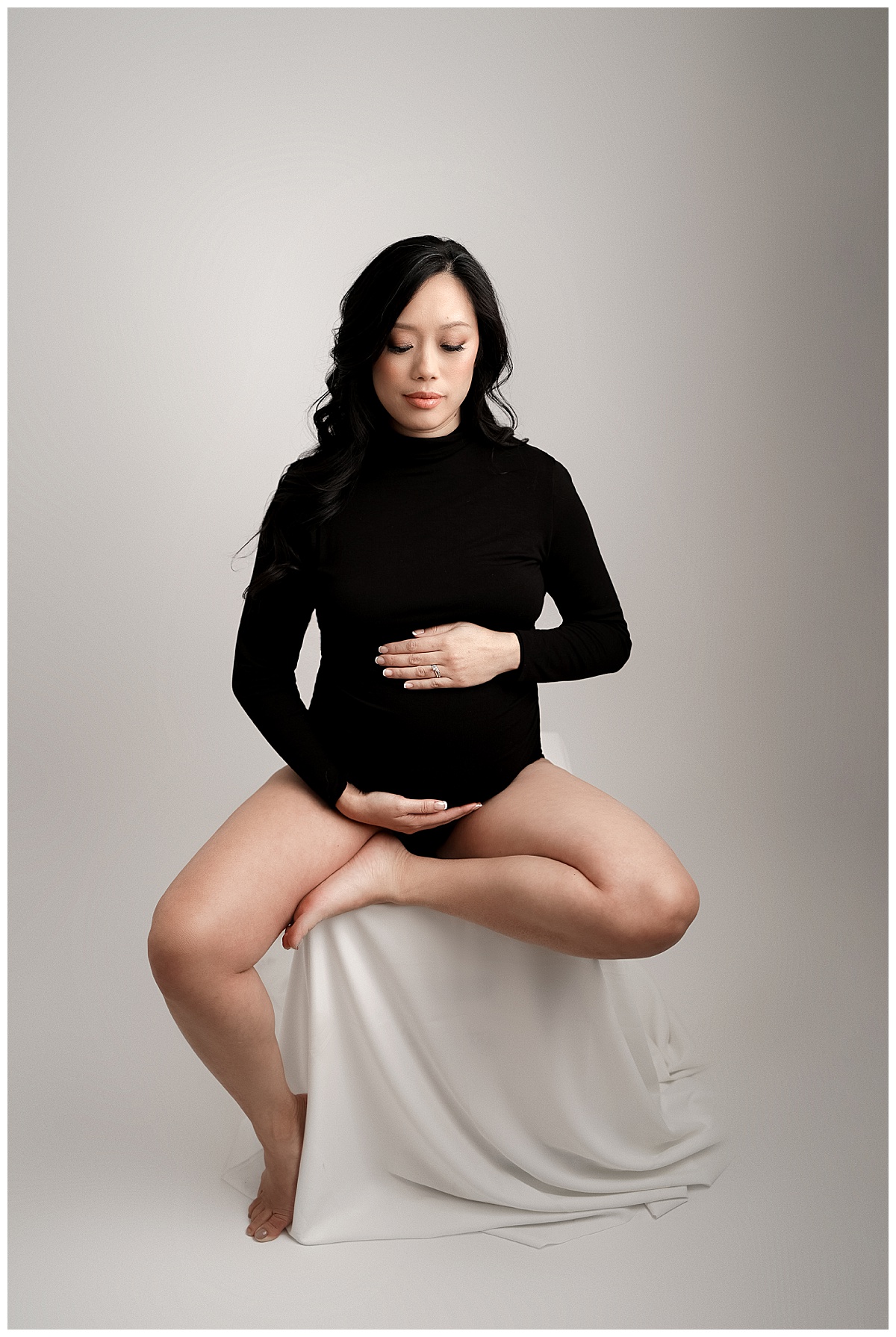 Woman holds her hand on her belly wearing a black outfit for Yaffa Koff Photography