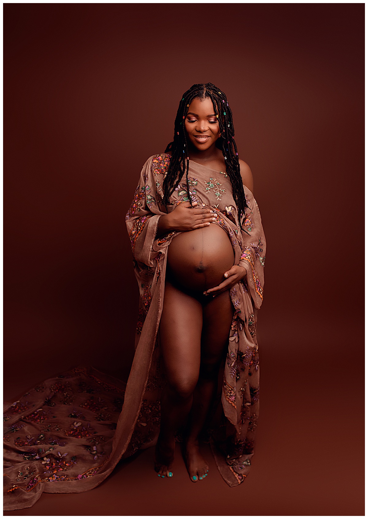 Adult looks stunning holding onto her pregnant belly showing Why I Include Hair And Makeup For All Maternity Sessions