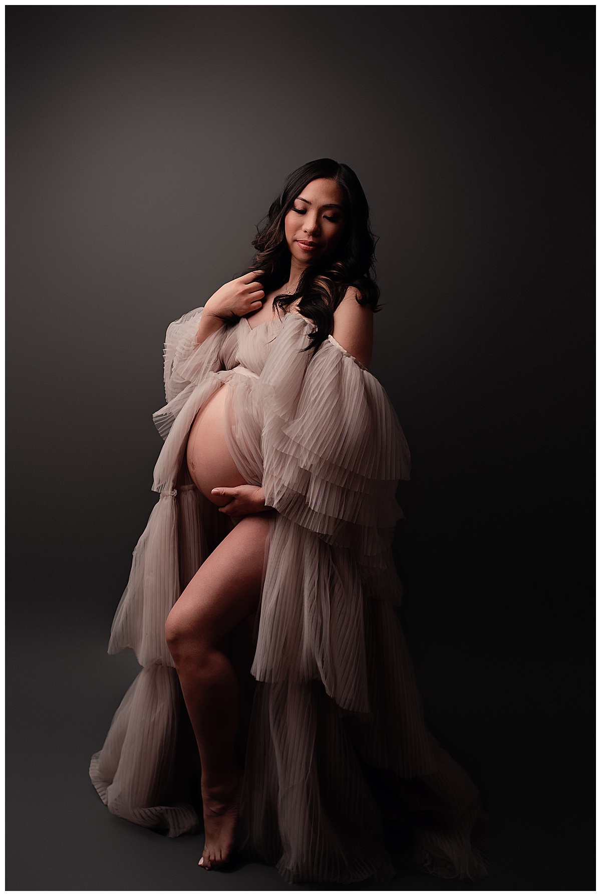 Female looks stunning holding onto her pregnant belly showing Why I Include Hair And Makeup For All Maternity Sessions