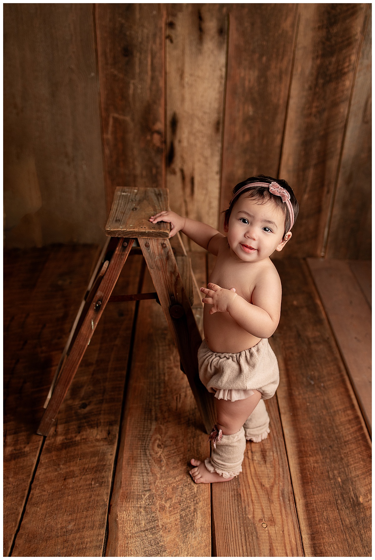 Baby holds onto a ladder for Silver Spring Newborn Photographer