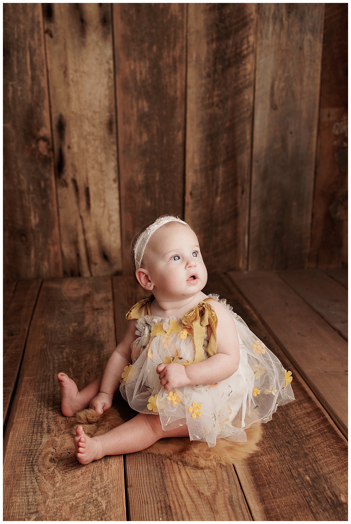 Baby sits on the floor looking up for Yaffa Koff Photography