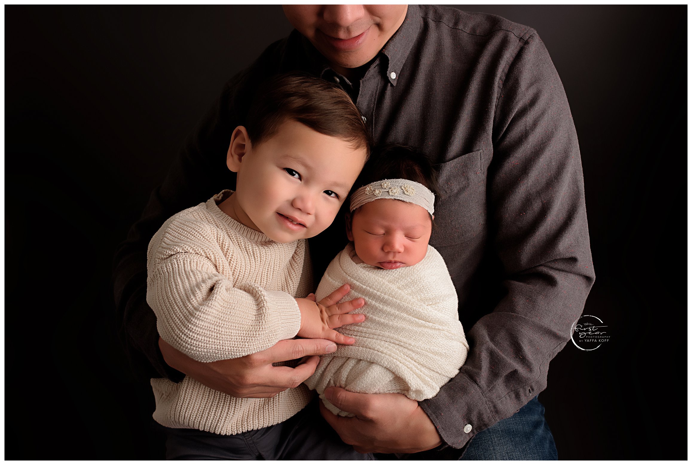 Young child holds baby close showing why you should have Siblings In A Newborn Session