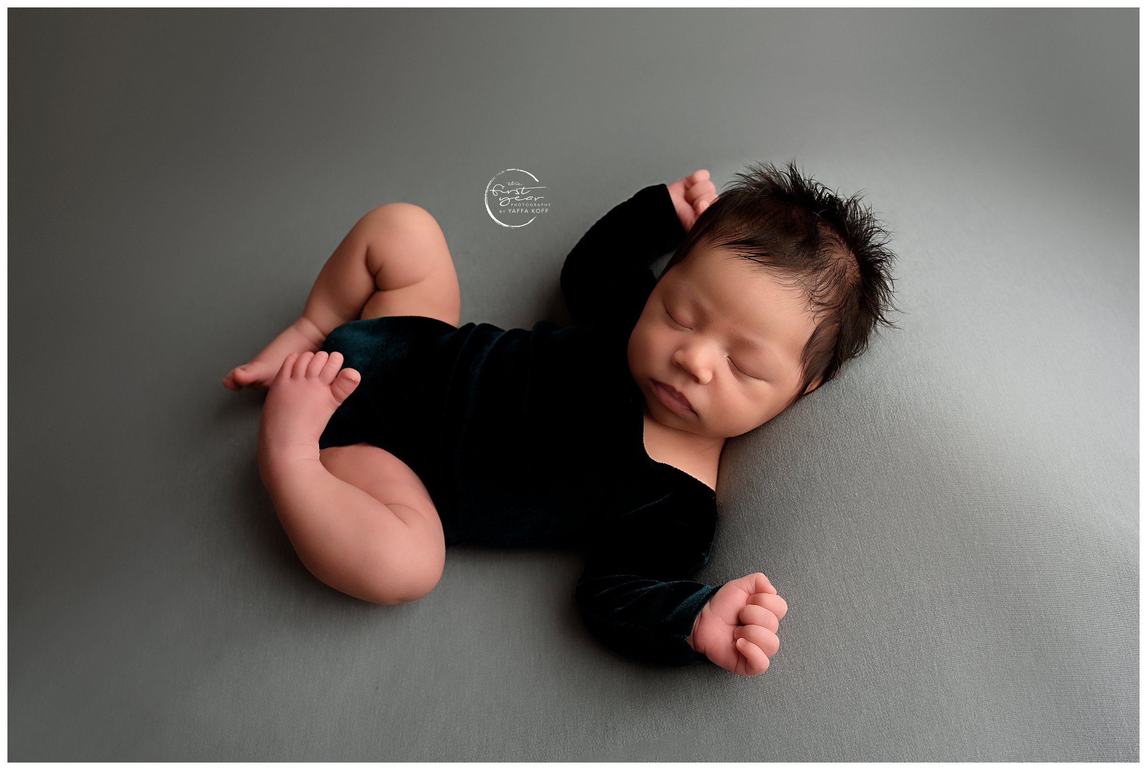 Baby lays down wearing a black onesie for Silver Spring Newborn Photographer