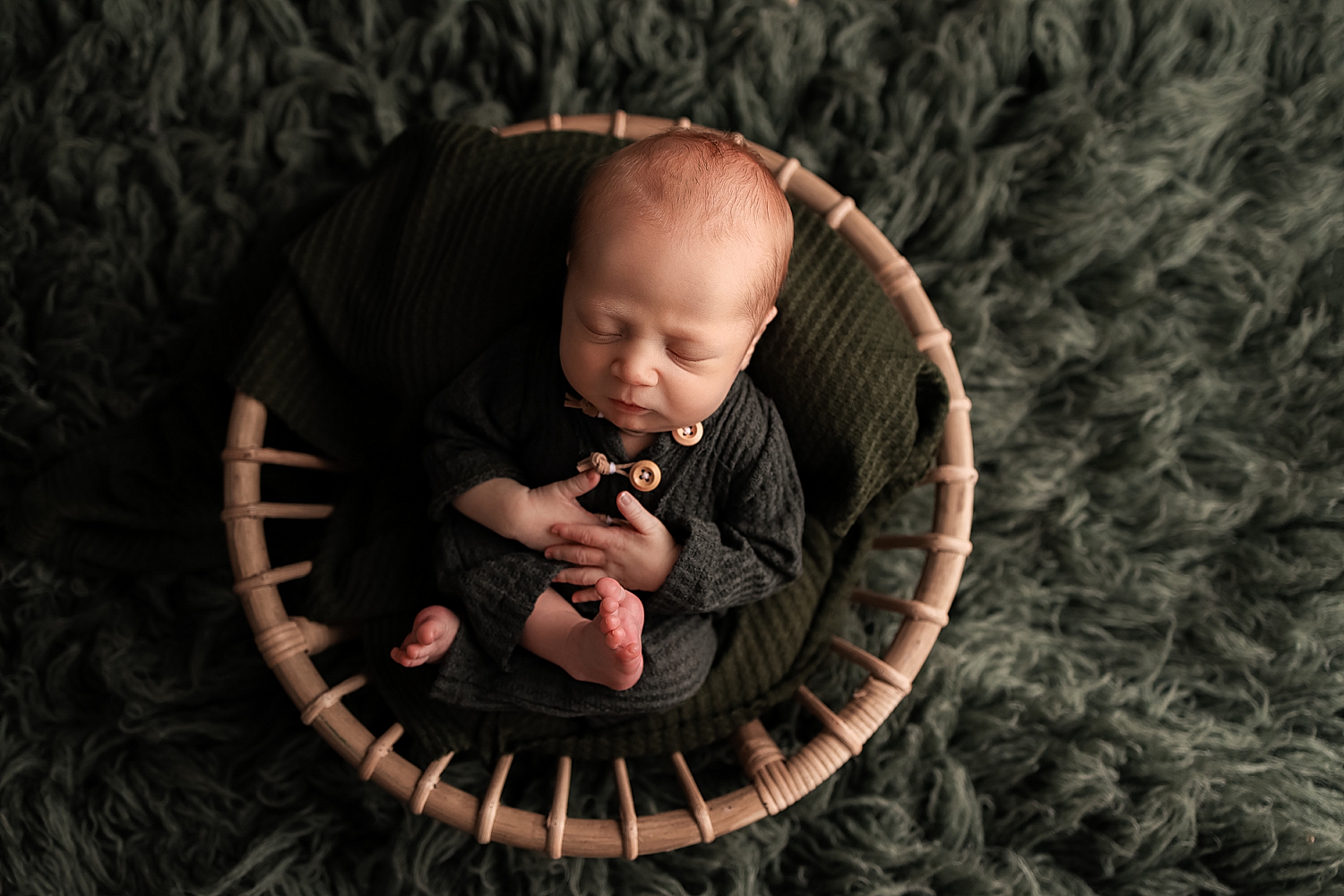 infant in a basket wearing green for neutral outfits for newborn sessions