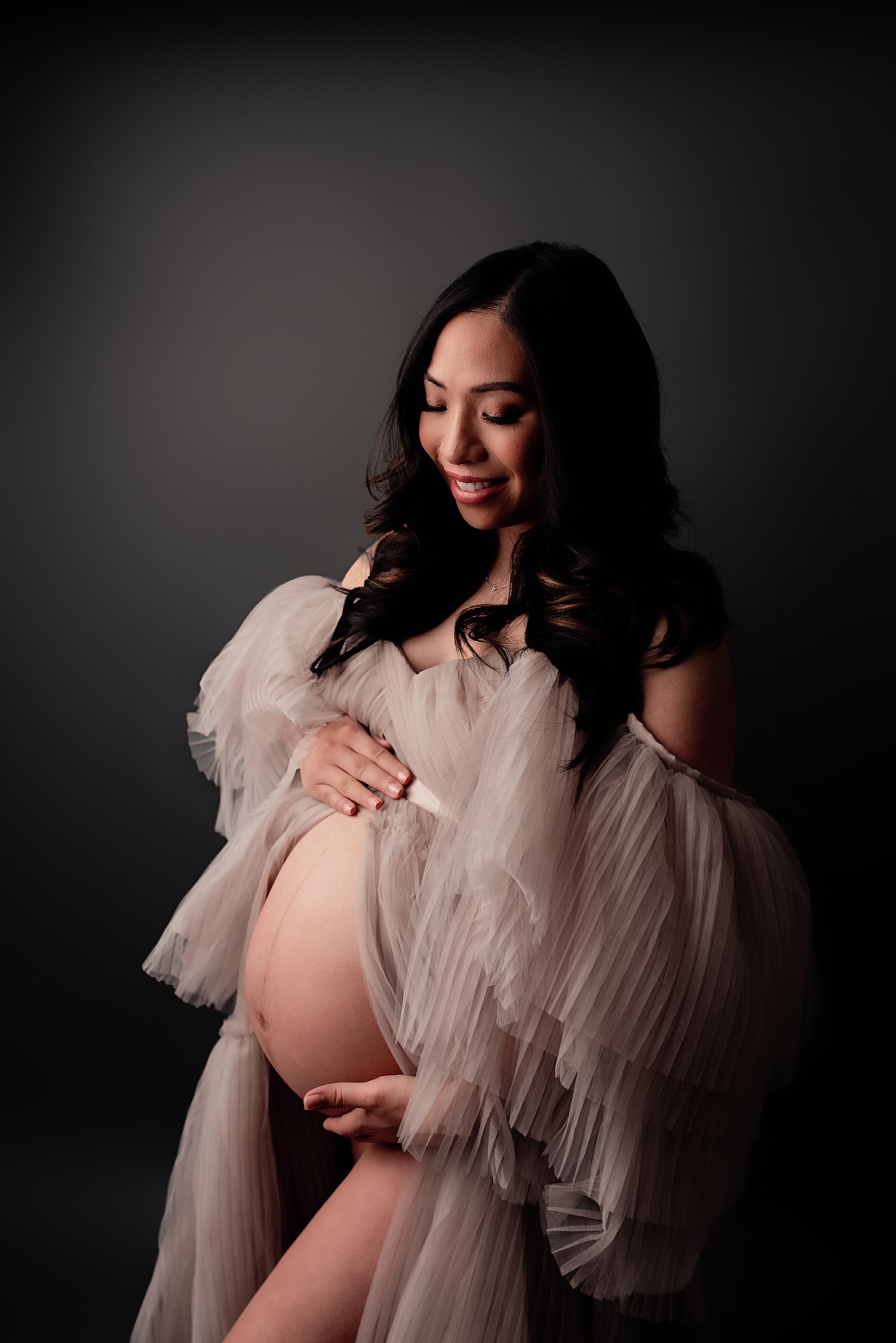 mother cradles her belly in studio by Yaffa Koff Photography